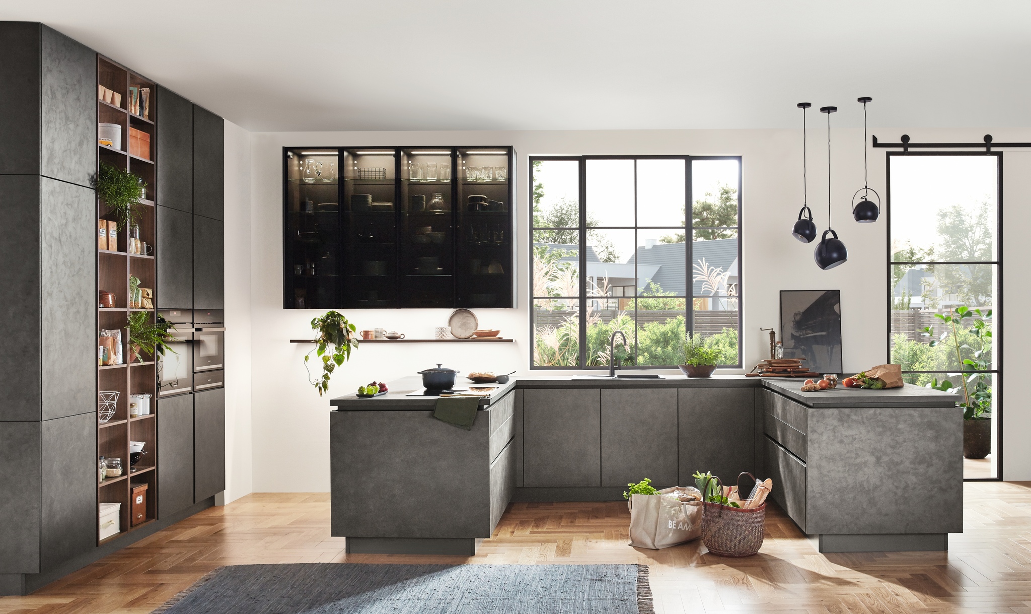 Expansive industrial-style kitchen featuring dark gray concrete-finish cabinets, a large island, black pendant lights, and large windows.