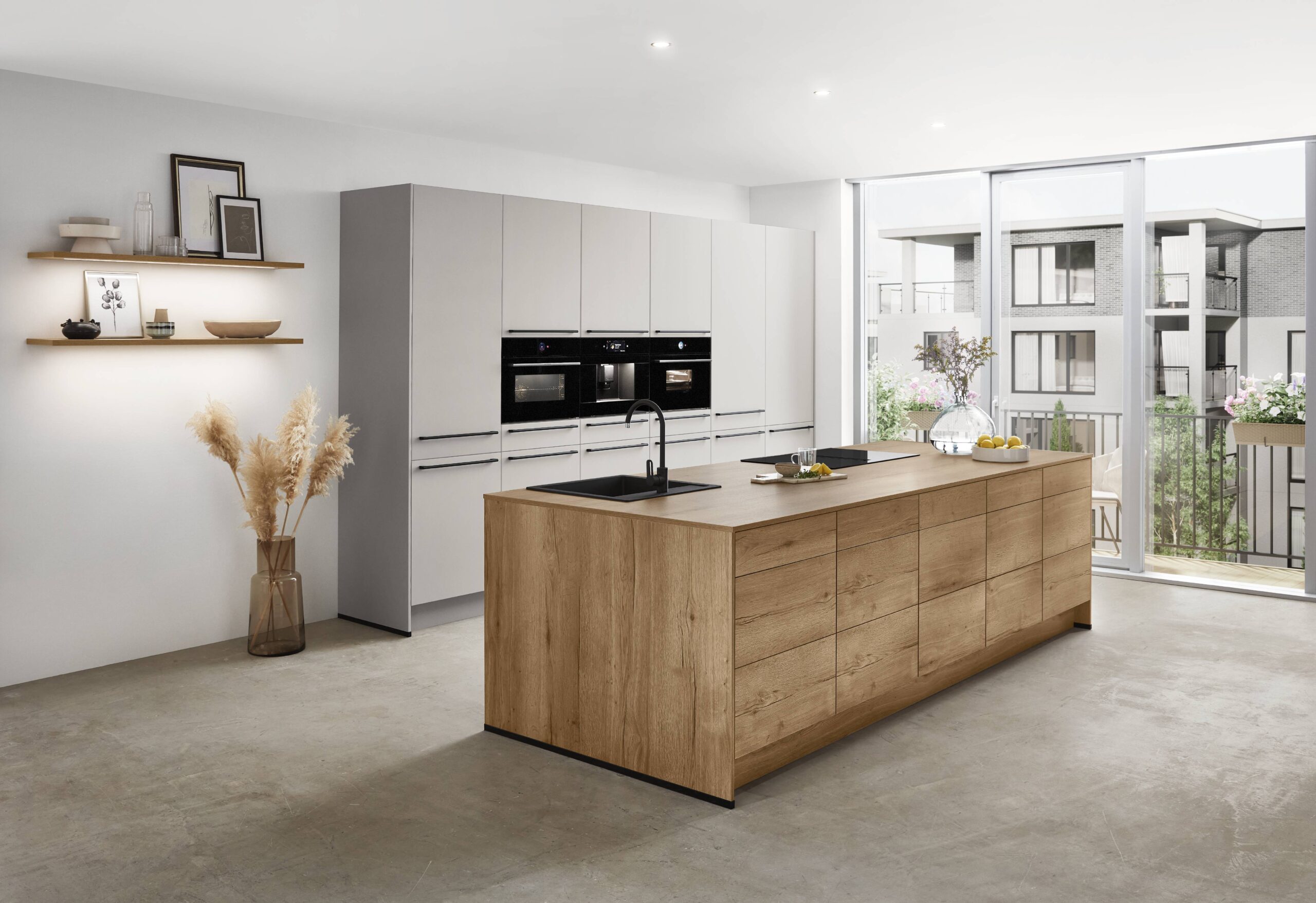 Modern kitchen with light gray cabinets, a large wood island, black appliances, and a large window offering a view of a balcony.