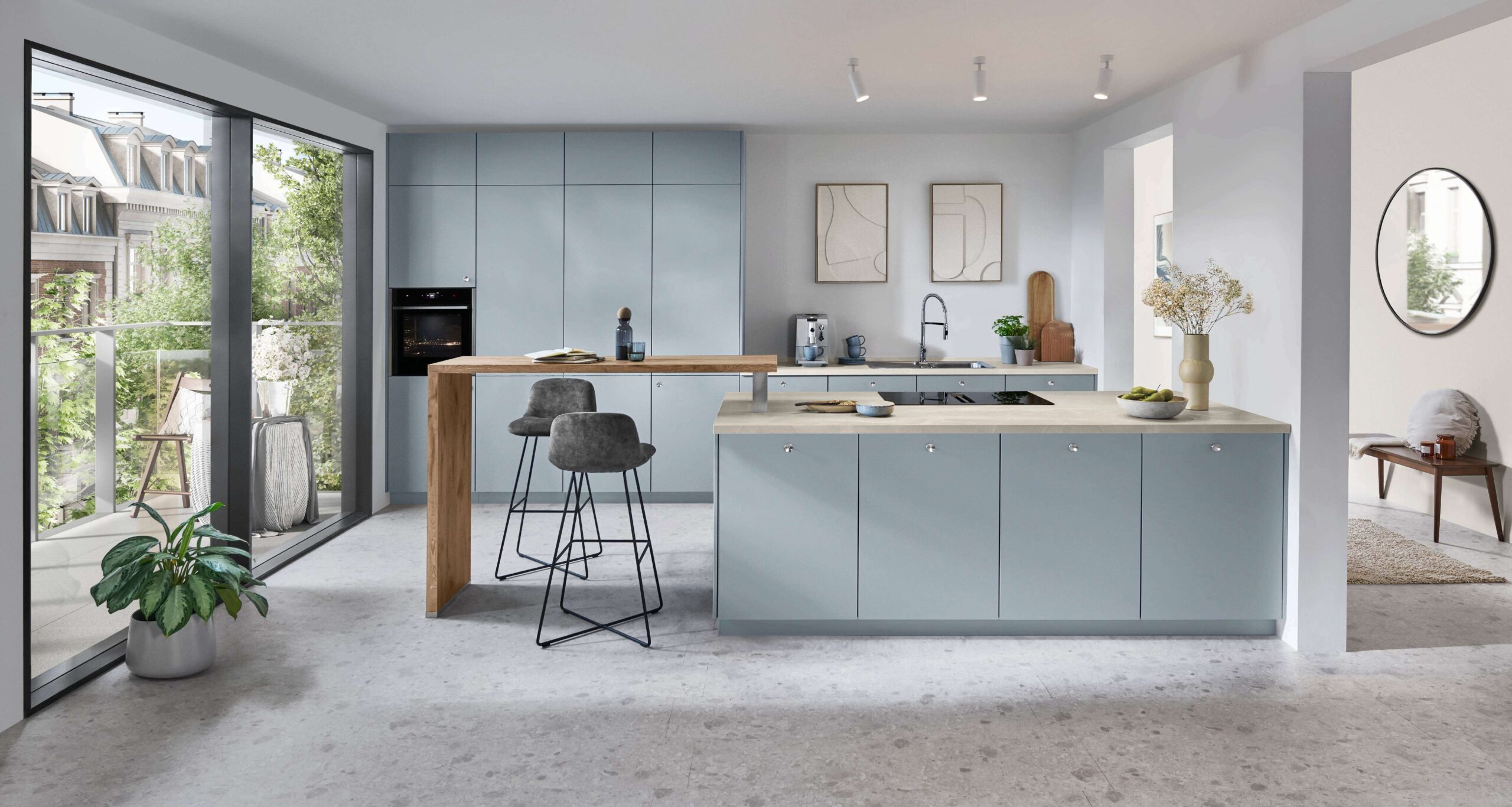 Contemporary light blue kitchen with a light-colored countertop island, a wood breakfast bar, black bar stools, and large windows.