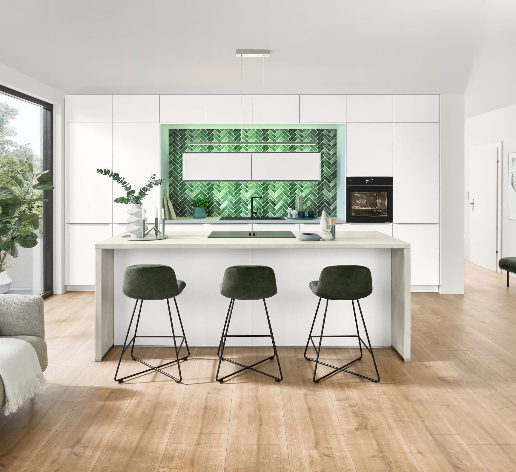 Modern kitchen with white cabinets, wood floors, a green herringbone backsplash, and a central island with green bar stools.
