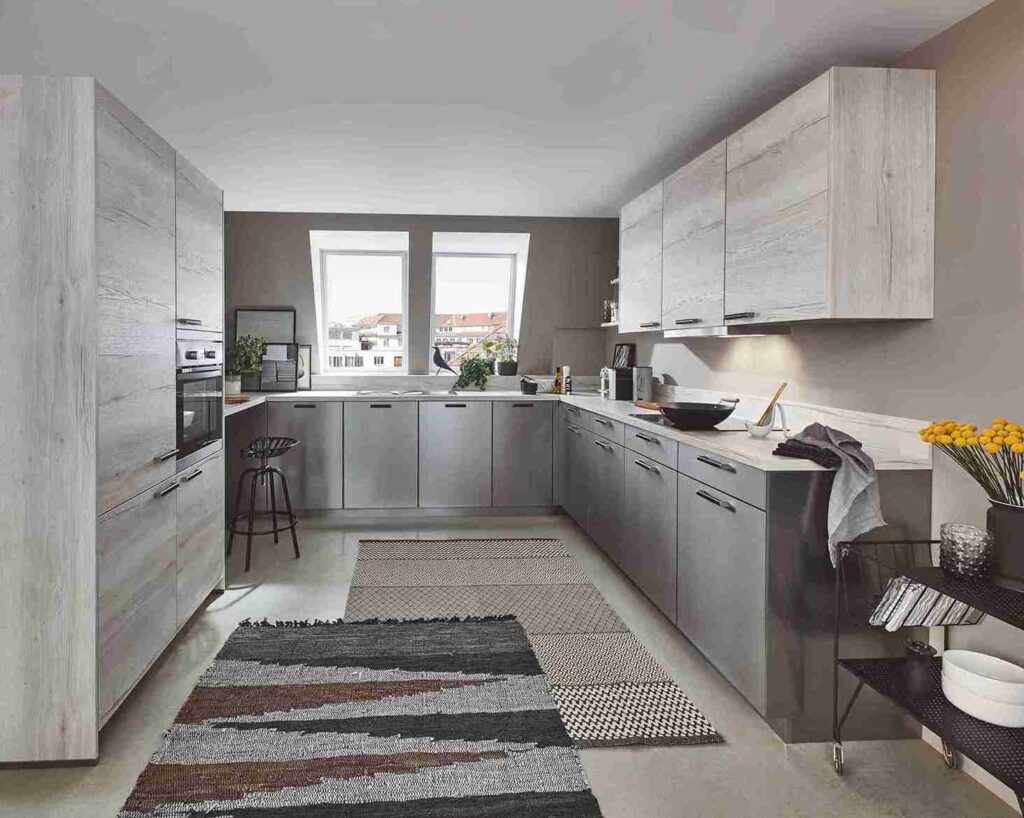 This grey and wood kitchen highlights a sleek, durable floor, offering inspiration for those considering the best kitchen flooring material for a similar style. A patterned rug adds warmth.