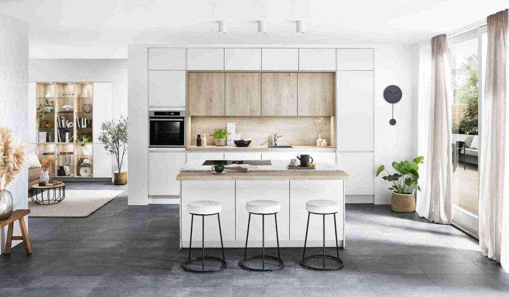 A minimalist white and wood kitchen showcases a large-format tile floor, offering a practical and stylish option for those searching for the best kitchen flooring material.