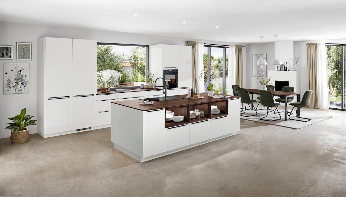 A bright and spacious kitchen featuring a white island with wooden accents and a modern dining table setup.