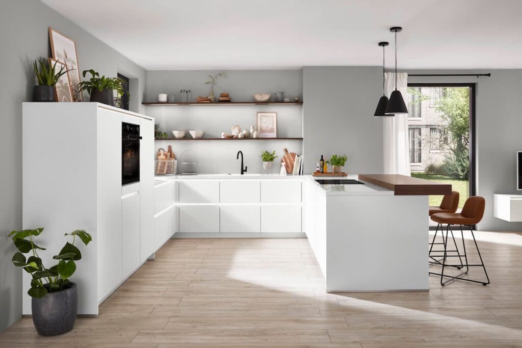 A clean, white kitchen with an open layout and light wood-style high-traffic flooring material, offering both elegance and resilience for daily use.