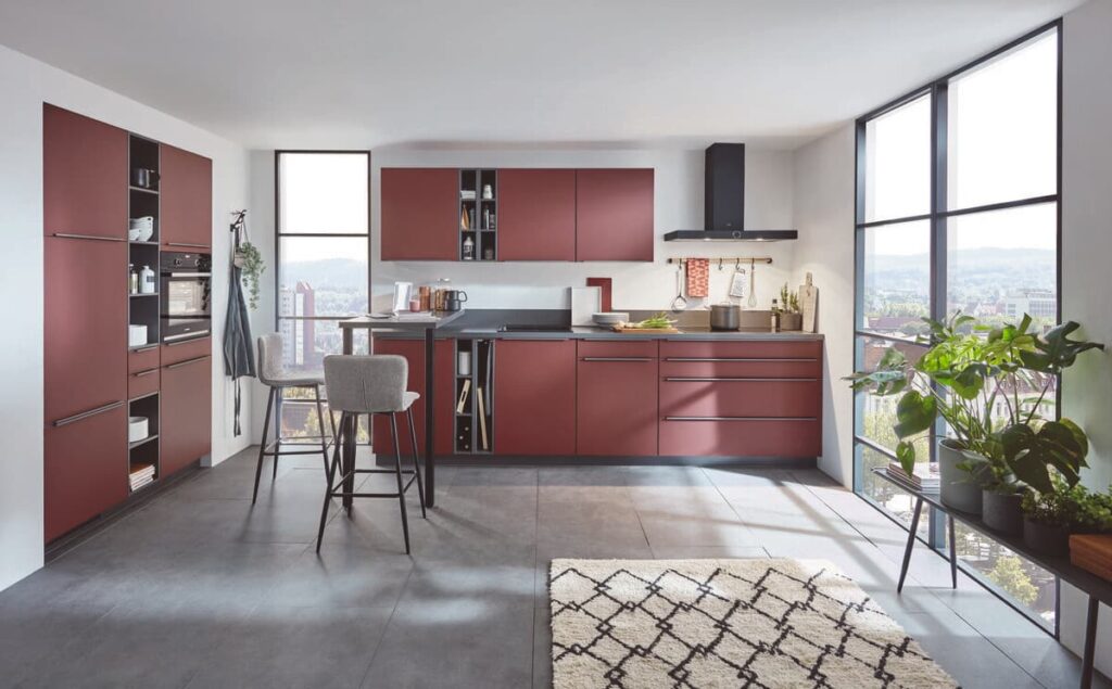 Contemporary kitchen with polished concrete flooring, burgundy cabinets, and large windows, highlighting one of the best kitchen flooring materials for a sleek, modern look.