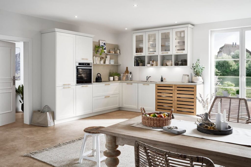 A bright, cottage-inspired L-shaped modular kitchen interior design, featuring white cabinets and wooden accents, creating a warm and inviting cooking space.