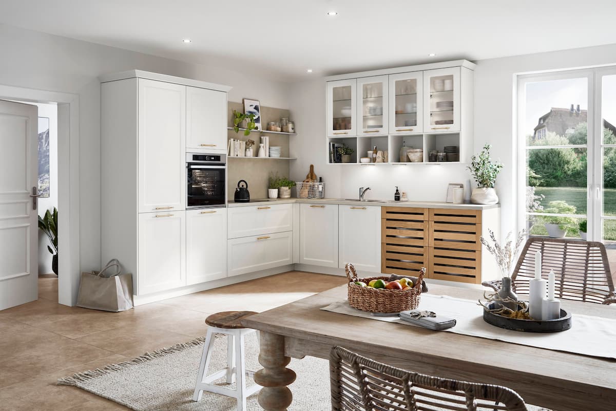 A bright, cottage-inspired L-shaped modular kitchen interior design, featuring white cabinets and wooden accents, creating a warm and inviting cooking space.