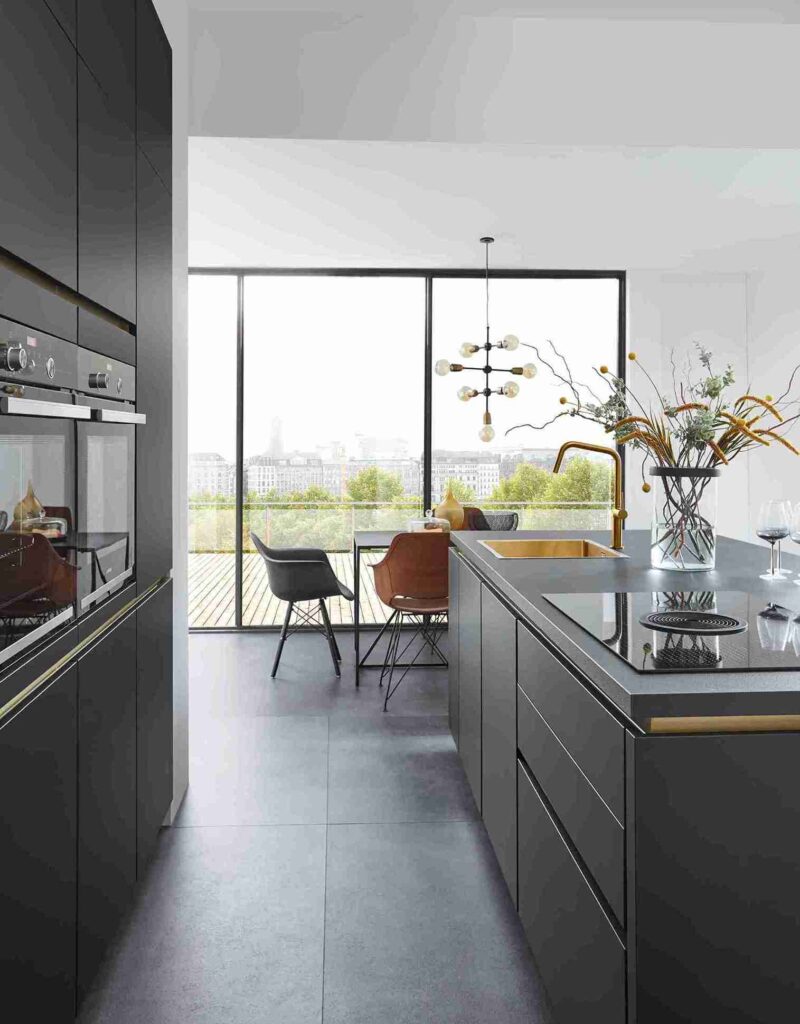 A modern custom-made kitchen with black cabinetry and a city view. The streamlined design emphasizes the clean lines and functionality achieved with custom joinery.