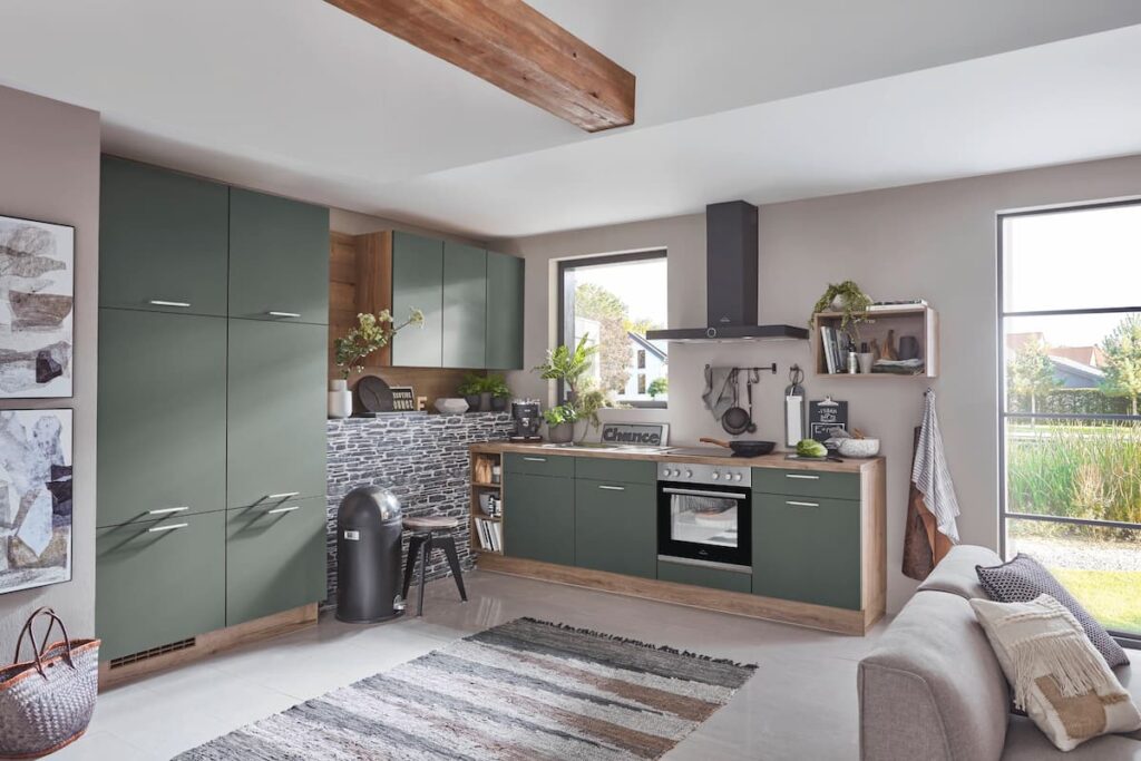 A cozy L-shaped modular kitchen interior design in earthy green tones, with wooden beams and a stone backsplash, blending rustic charm with contemporary functionality.