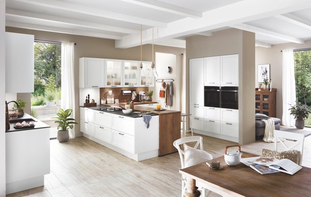 An open-plan eco kitchen design featuring white cabinets, wood accents, and ample natural light, creating a bright and airy space.