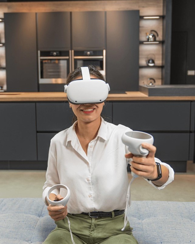 A woman uses a VR headset in a German kitchen showroom, experiencing an immersive kitchen design visualization.