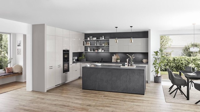 A sophisticated high-end German kitchen combining light gray cabinets with a dark gray island and wood flooring.