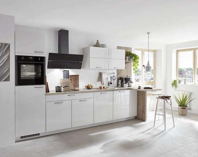 A contemporary high-end German kitchen with white gloss cabinets, a striking black range hood, and wood accents.