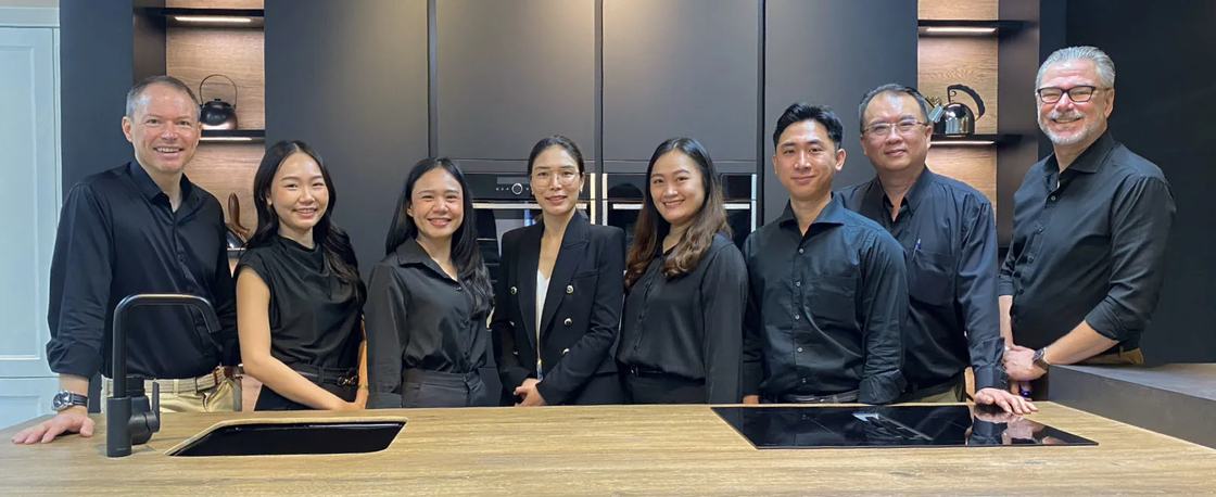 German Kitchen Design's team in black shirts posing in their modern kitchen showroom at River City Bangkok.