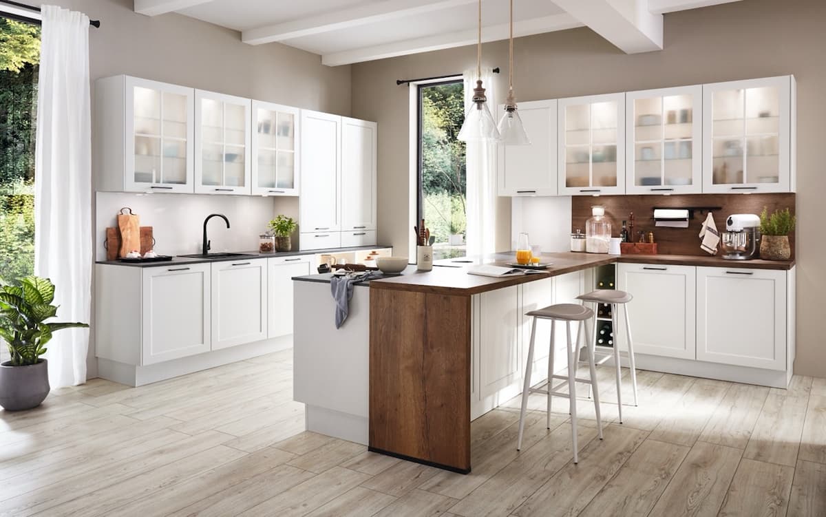 A bright white kitchen with a wood island. This design prompts the question: How much should I spend on a kitchen to achieve a similar look and feel?