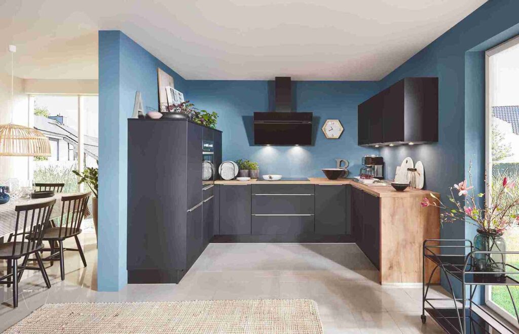 A modern kitchen with blue walls and dark grey cabinets, showcasing a light-colored floor as a potential best kitchen flooring material for a contemporary space.