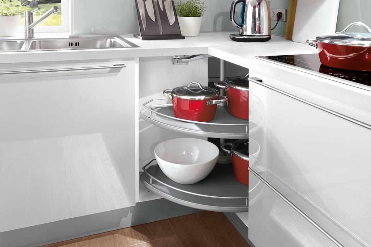 Clever kitchen interior design maximizing corner cabinet storage with a pull-out swivel shelf. This solution keeps cookware organized and accessible.