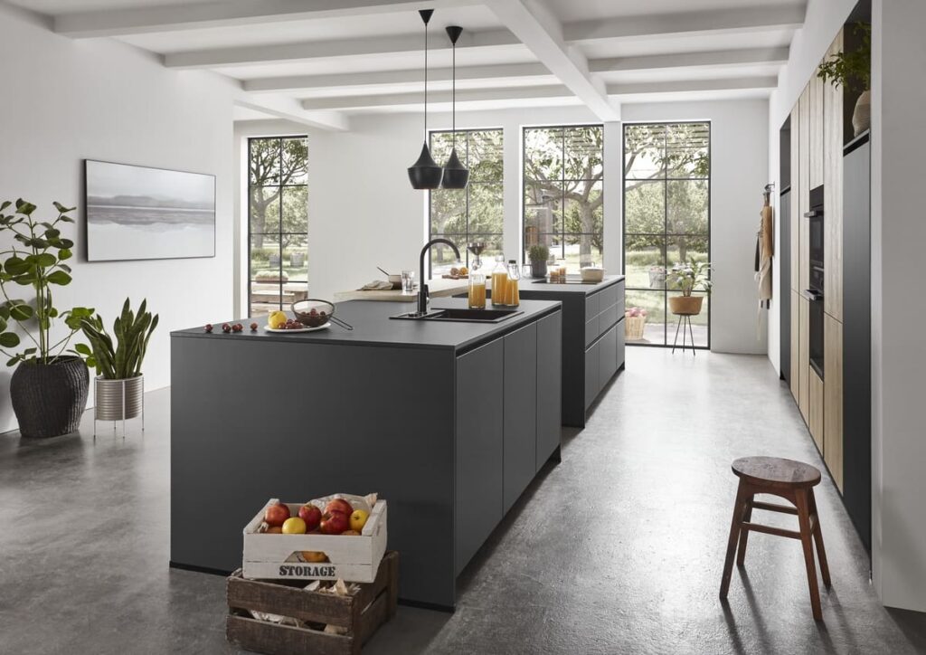 Minimalist kitchen with polished concrete flooring, black cabinets, and open windows to the garden, perfect for showcasing the best kitchen flooring material for a sleek and functional space.