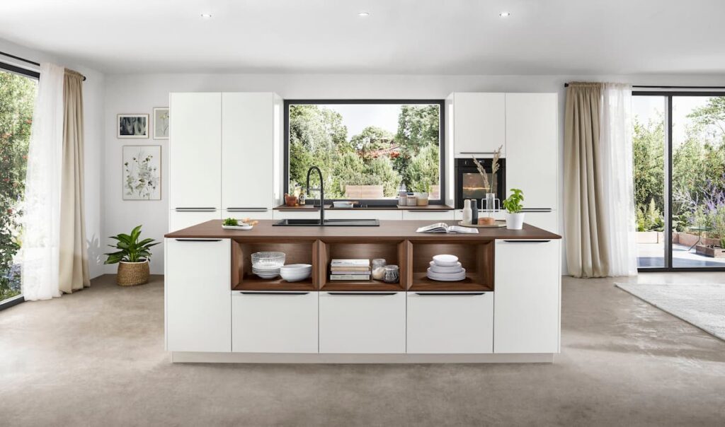 A spacious, minimalist kitchen with bright white modular cabinets showcasing the best material for modular kitchen cabinets, adding warmth with natural wood accents.