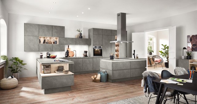 A modern kitchen featuring gray cabinets, a large island, integrated appliances, and warm wood flooring. The sleek design highlights potential options for the best material for kitchen cabinets in a contemporary setting. 