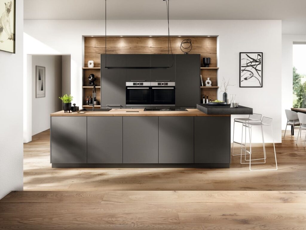 Modern kitchen with oak wood flooring, featuring dark gray cabinets and a wooden countertop island, ideal for exploring the best kitchen flooring material options.