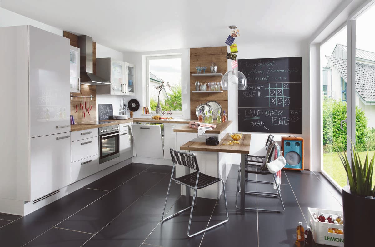 A white modern kitchen with a chalkboard accent wall. The streamlined design incorporates built-in appliances and cabinetry for a cohesive look.