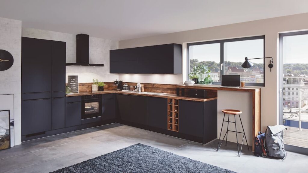 A sleek, modern L-shaped modular kitchen interior design with matte black cabinets and wooden countertops, perfect for compact urban spaces with a stylish edge.