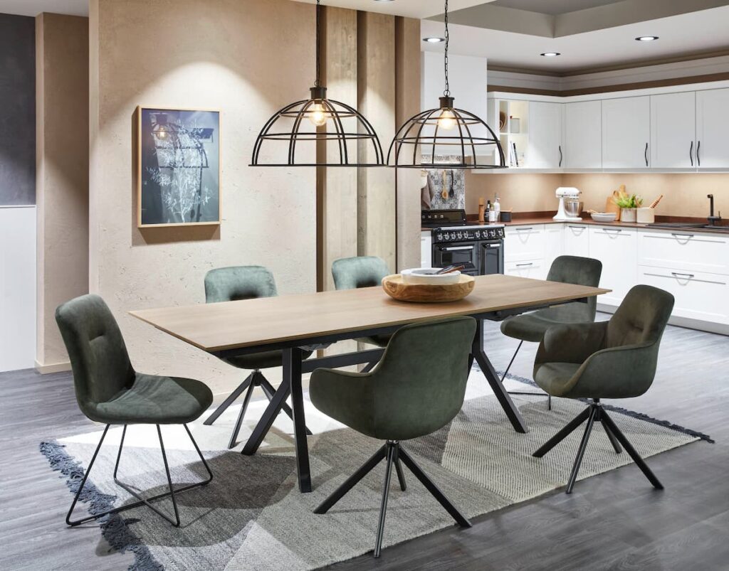 A rustic dining room with green chairs and a wooden table, showcasing eco-friendly kitchen design with natural materials and sustainable lighting.