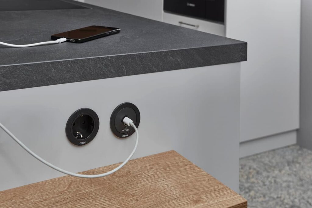 A luxury kitchen detail highlighting latest electrical solutions, featuring integrated plugs in a stone countertop.