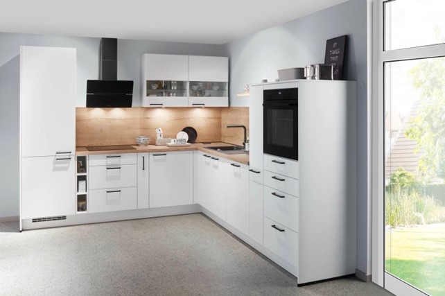 Modern L-shaped kitchen interior design with sleek white cabinets, wooden backsplash, and integrated appliances, highlighting tips and trends for a functional and stylish kitchen layout.