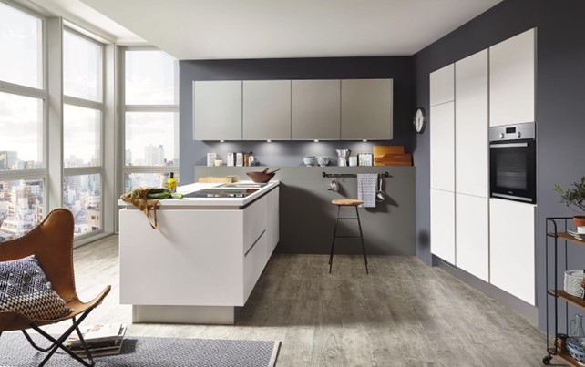 A clean and minimalist approach to "what colour goes with grey kitchen units" uses white cabinets and a contrasting dark gray wall, showcasing a bright and airy design.
