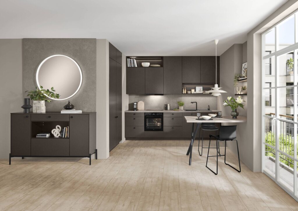 A stylish, compact dark matte kitchen featuring handleless cabinetry, built-in appliances, and a round mirror, part of a functional-yet-aesthetic design for minimal kitchens.