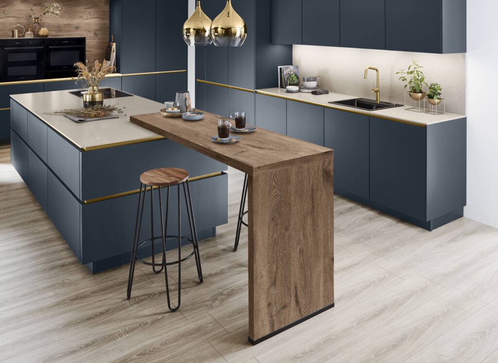 Modern kitchen design featuring navy cabinetry, light worktops, and a wooden breakfast counter with bar stools.