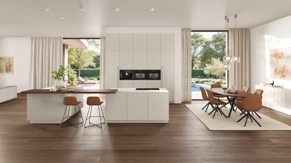 Bright minimalist white kitchen with integrated dining area and garden view for a natural living atmosphere.