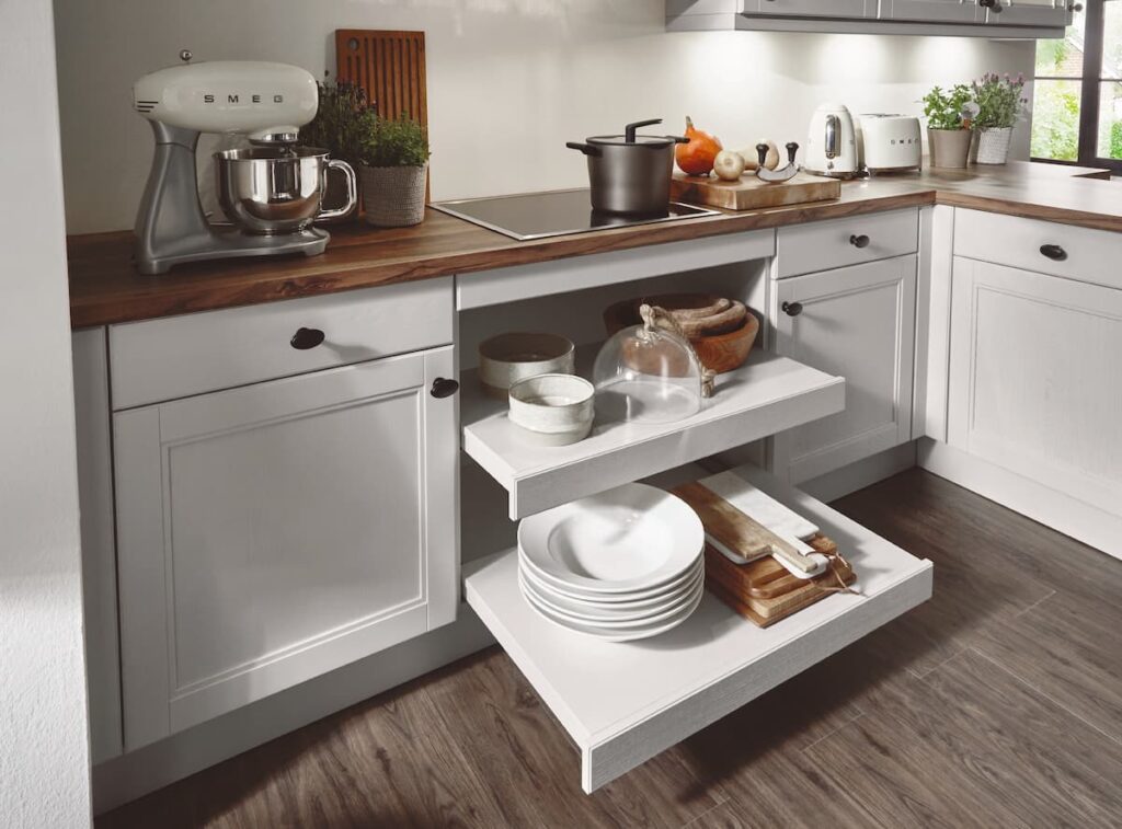 White framed cabinet featuring a pull-out shelf mechanism, blending modern functionality with the aesthetic of country kitchens.