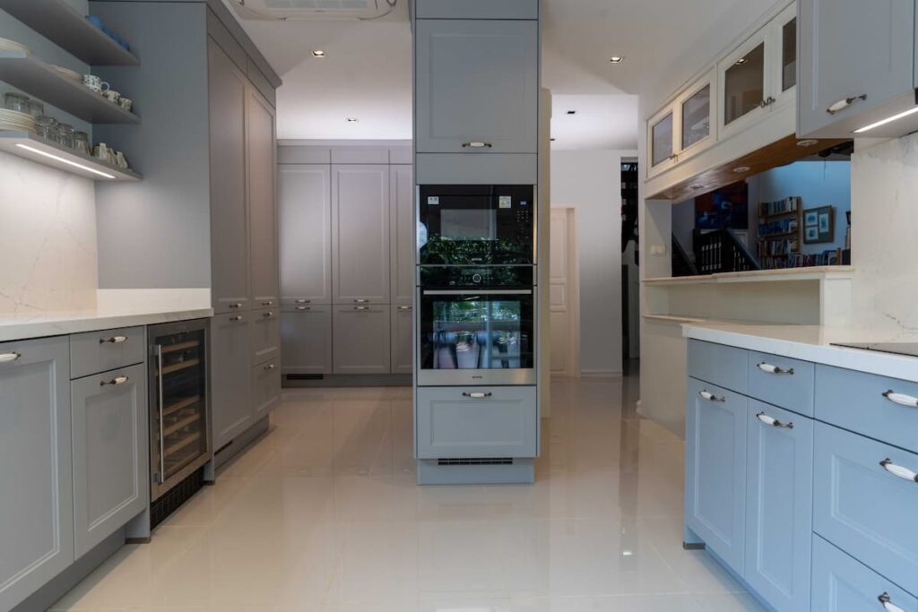 A view of a modern kitchen aisle featuring integrated wall ovens and smart appliance placement to ensure an ergonomic flow and easier movement. 