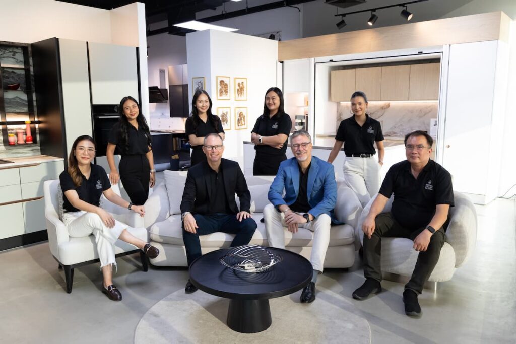 A team of professional designers in a kitchen showroom, ready to assist clients in comparing factory-engineered systems with a traditional built in kitchen.