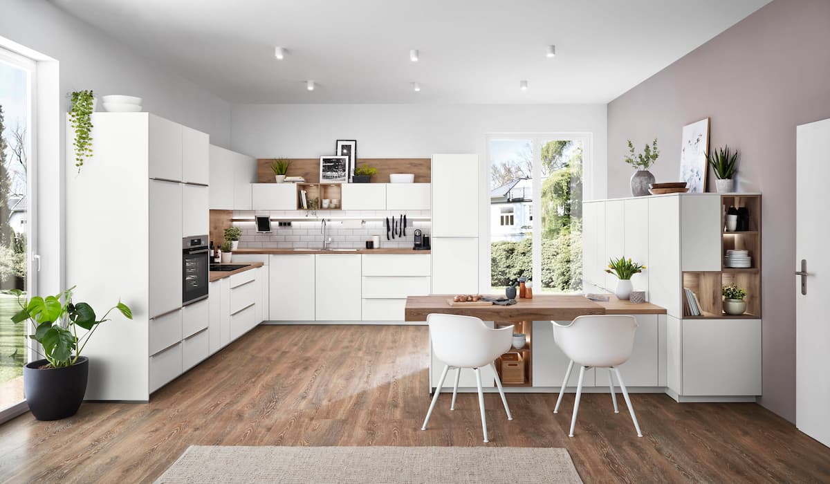 A spacious modern kitchen featuring an ergonomic kitchen island with an attached breakfast table, promoting comfort and improved workflow in the home.