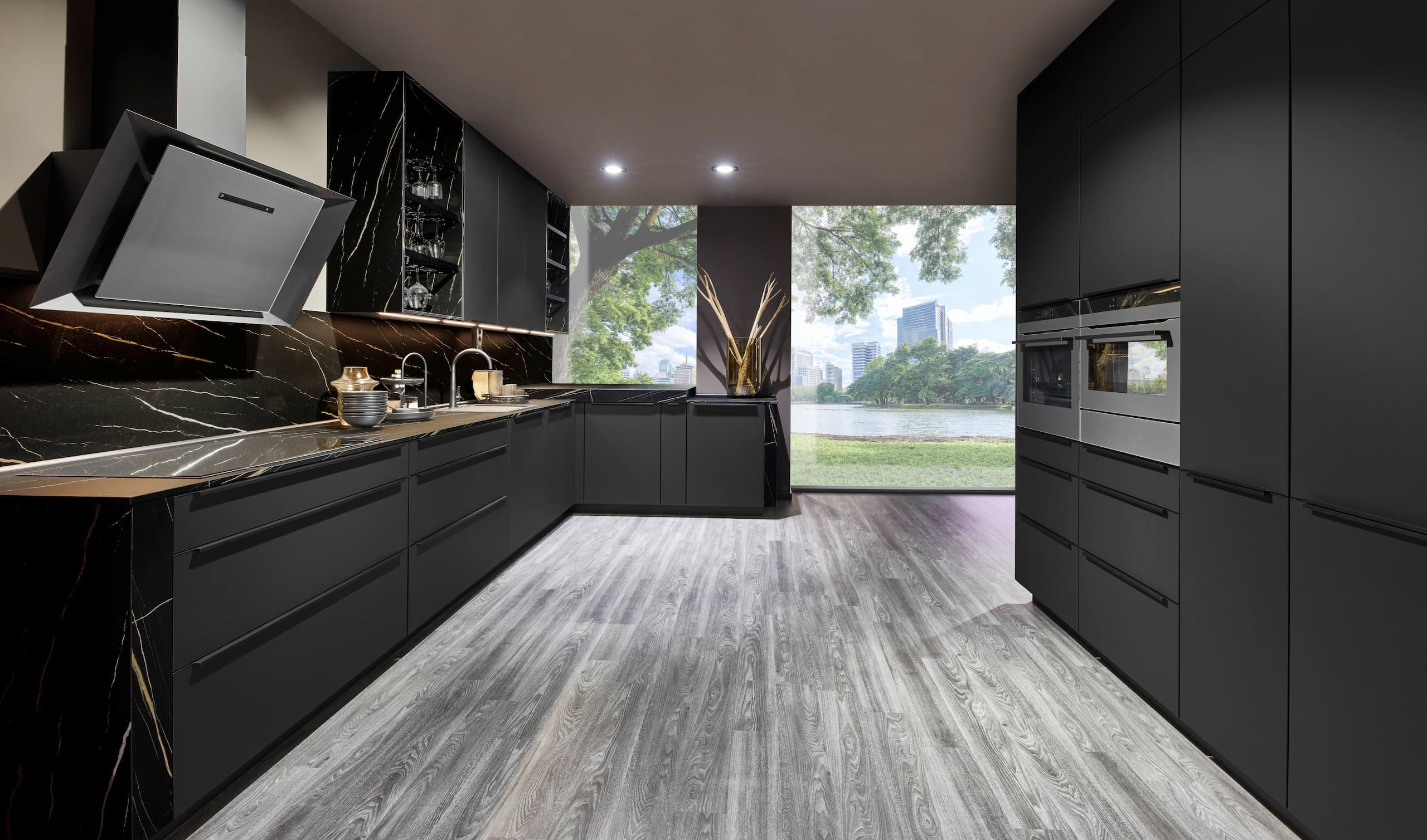 A dramatic modern German kitchen showcasing seamless graphite black ultra matt cabinetry with slim horizontal matching handles, paired with a striking black and gold-veined marble backsplash and worktops, dark tinted glass-front upper displays, and integrated stainless steel double ovens.