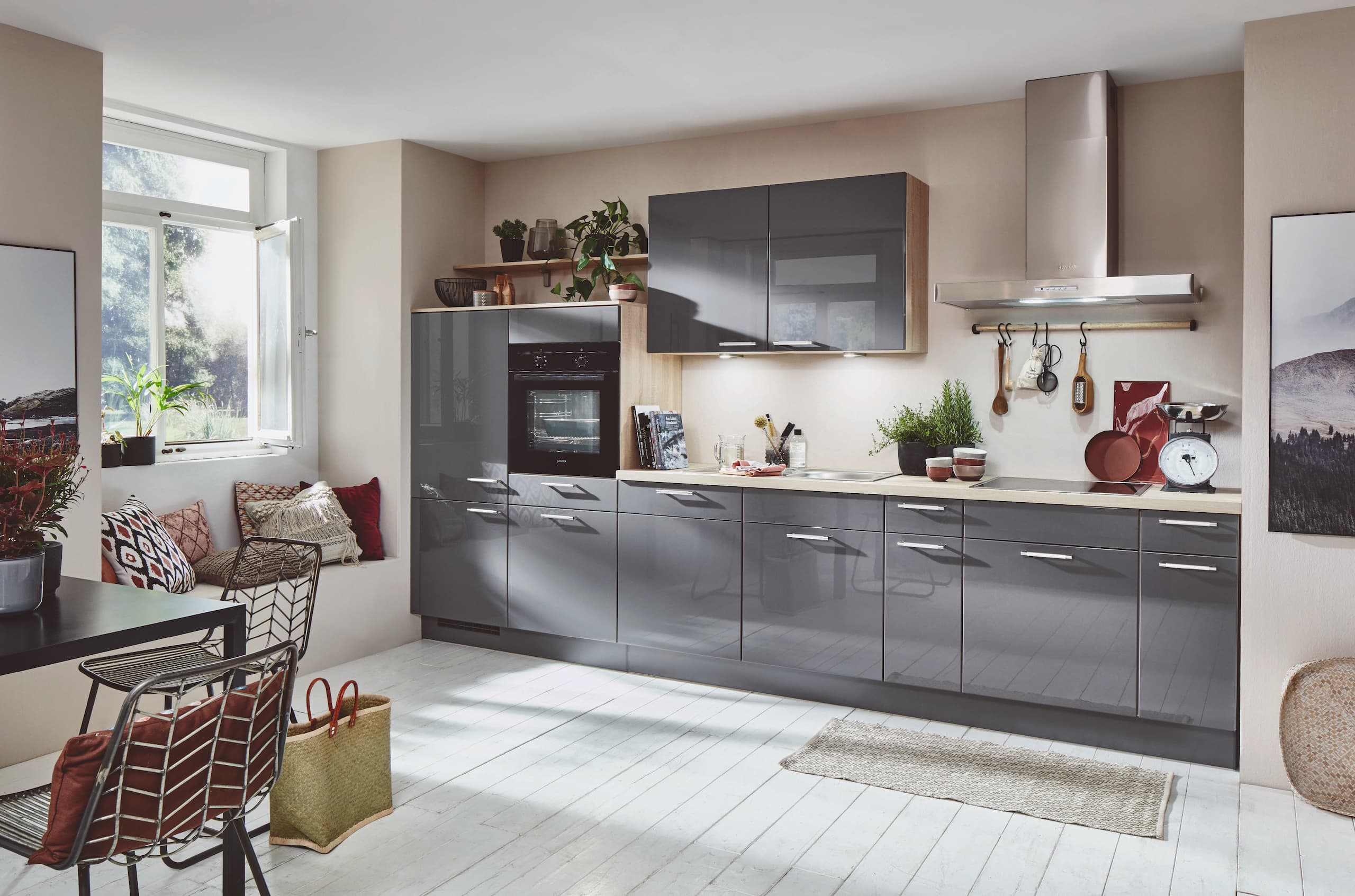 A contemporary linear German kitchen featuring sleek slate grey high gloss cabinetry with clean stainless steel bow handles, framed by warm natural wood-grain shelving and side panels, a matching light wood worktop, and an elevated integrated black oven tower.
