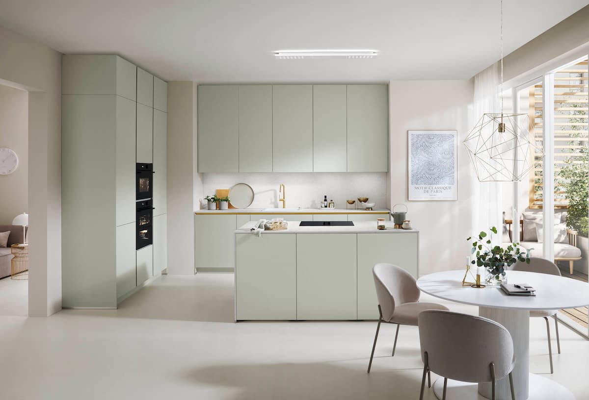 A minimalist handleless German kitchen showcasing seamless premium honed jade fronts, a matching central kitchen island, a white countertop, and integrated gold profile accents in a bright, sophisticated contemporary dining area.